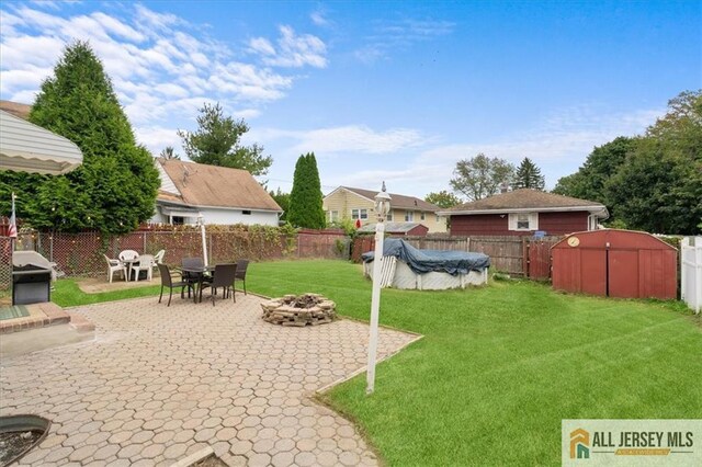 view of yard with a covered pool, a patio area, and a fire pit