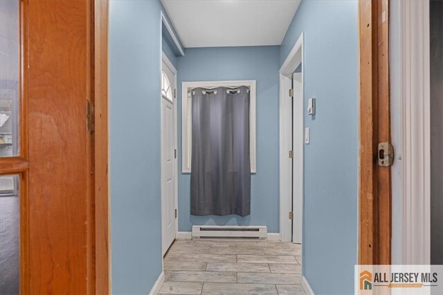 corridor with a baseboard heating unit and light hardwood / wood-style floors