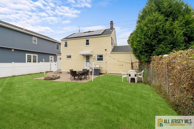 rear view of house featuring a patio, a yard, and solar panels