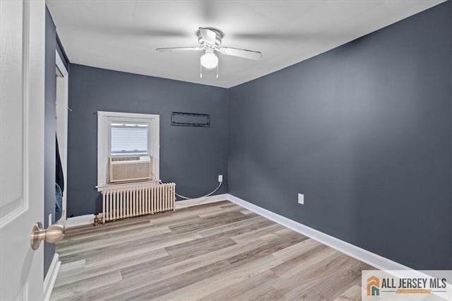 unfurnished room featuring cooling unit, ceiling fan, radiator, and light wood-type flooring