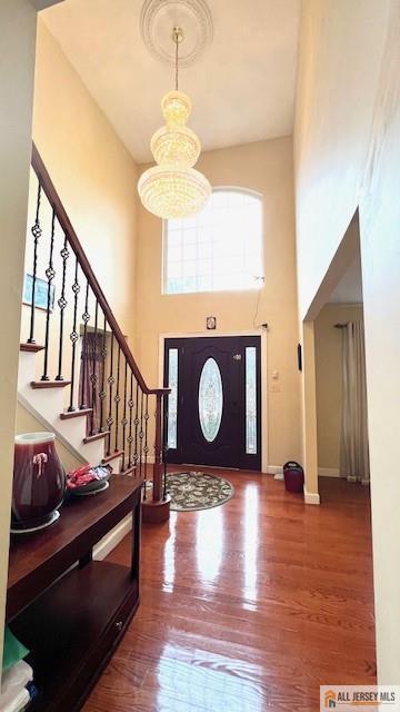 entrance foyer featuring hardwood / wood-style floors, a towering ceiling, and a chandelier