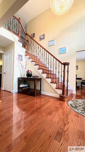 stairway featuring wood-type flooring and a towering ceiling