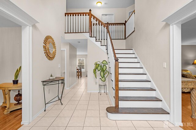 stairway featuring tile patterned floors and a high ceiling