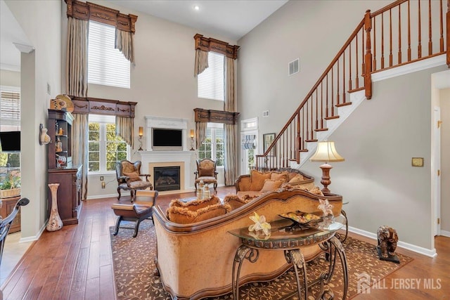 1 Ballybunion Dr, Monroe, NJ 08831 - living room featuring baseboards, a glass covered fireplace, hardwood / wood-style flooring, a high ceiling, and stairs