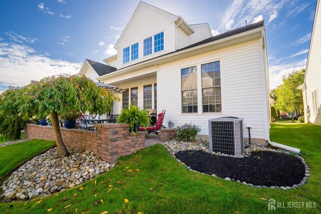 back of house featuring cooling unit, a yard, and a patio