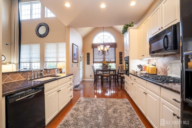 kitchen featuring sink, black appliances, and dark stone counters