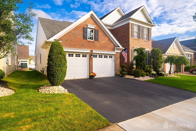 traditional-style home featuring a garage, driveway, brick siding, and a front lawn