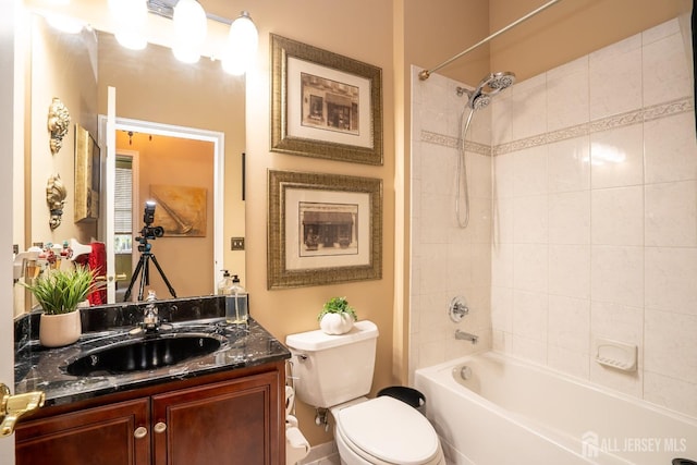 full bathroom featuring toilet, tiled shower / bath, and vanity