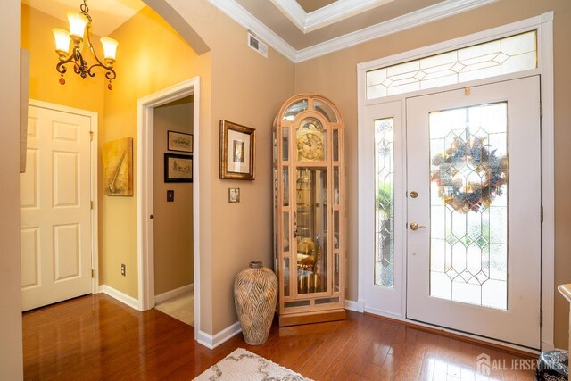 foyer with an inviting chandelier, crown molding, and hardwood / wood-style floors