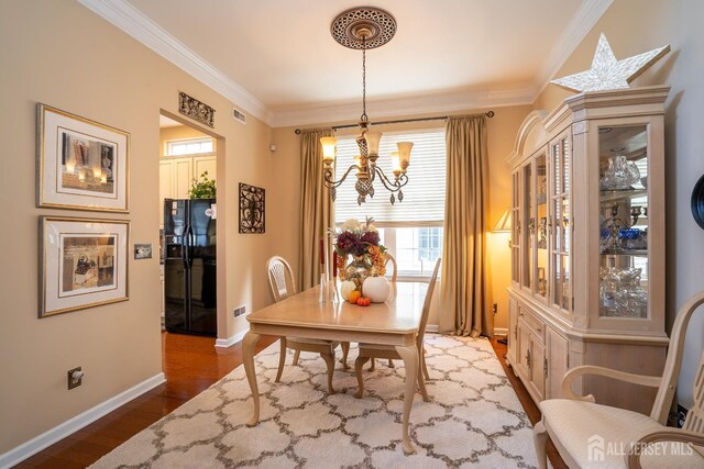 dining area with ornamental molding, an inviting chandelier, and wood-type flooring