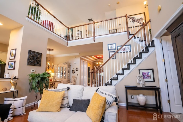 living room with dark hardwood / wood-style floors, ornamental molding, a towering ceiling, and an inviting chandelier