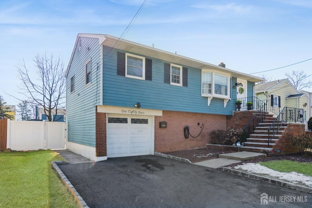 view of front of property with driveway, fence, stairway, an attached garage, and brick siding