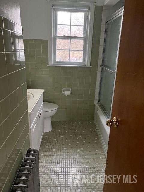 79 Davidson Mill Rd, South Brunswick, NJ 08902 - full bathroom with radiator, tile patterned floors, toilet, vanity, and tile walls