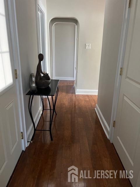 79 Davidson Mill Rd, South Brunswick, NJ 08902 - hallway featuring dark wood-style flooring, baseboards, and arched walkways