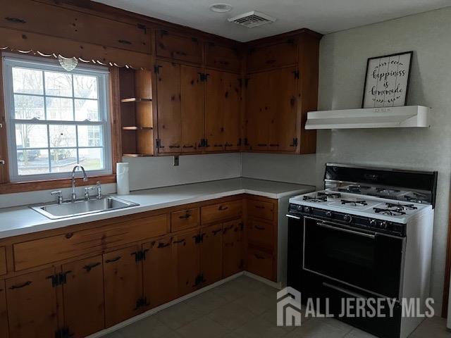 79 Davidson Mill Rd, South Brunswick, NJ 08902 - kitchen featuring range with gas cooktop, a sink, under cabinet range hood, light countertops, and brown cabinets