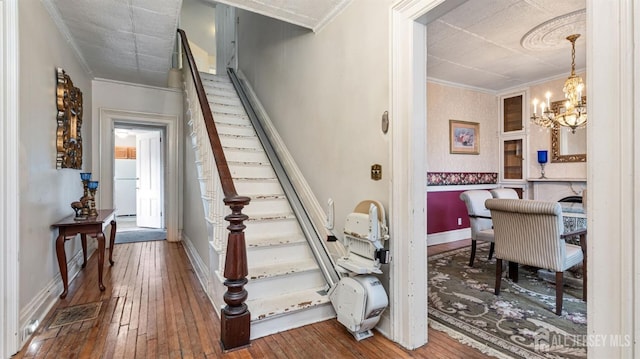 stairs with crown molding, wood-type flooring, and a chandelier