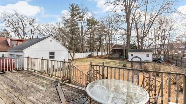 wooden deck featuring a yard and a storage unit