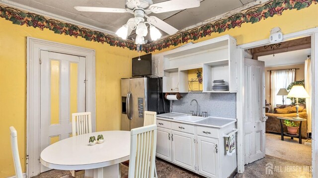 kitchen featuring white cabinetry, decorative backsplash, sink, stainless steel fridge, and ceiling fan