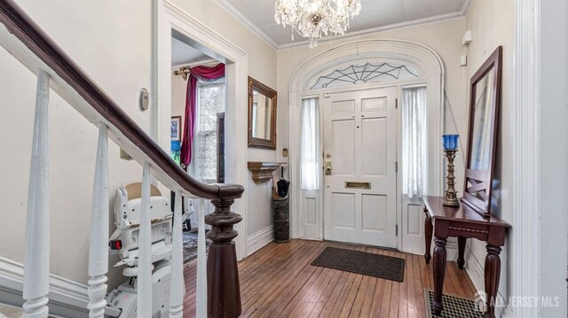 foyer featuring crown molding, an inviting chandelier, and hardwood / wood-style flooring