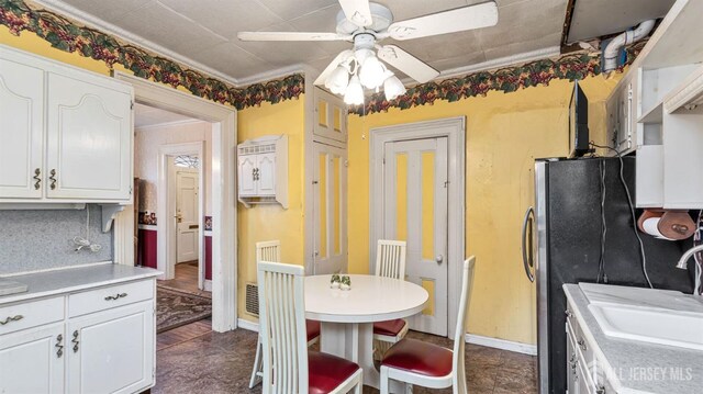 kitchen with ceiling fan, ornamental molding, white cabinets, and sink