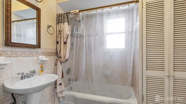 bathroom with tile walls, shower / bath combo, and sink