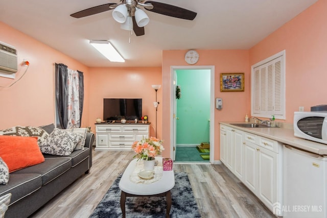 living room featuring ceiling fan, sink, a wall mounted air conditioner, and light wood-type flooring