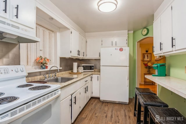 kitchen featuring sink, white cabinets, light hardwood / wood-style floors, and white appliances