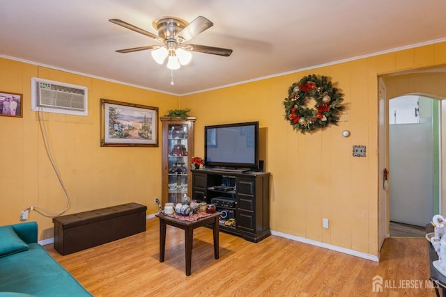 living room with a wall mounted air conditioner, ceiling fan, light wood-type flooring, and crown molding