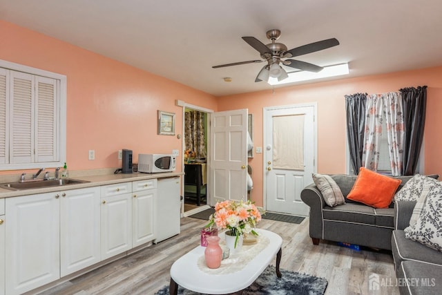 living room featuring light hardwood / wood-style floors, ceiling fan, and sink