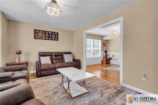 living area with a chandelier, wood finished floors, a wainscoted wall, and baseboards