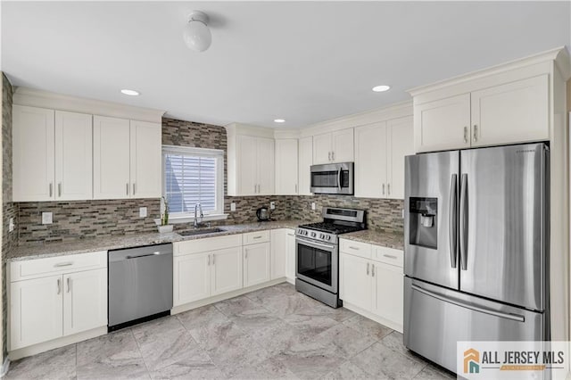 kitchen featuring stainless steel appliances, a sink, light stone counters, decorative backsplash, and recessed lighting