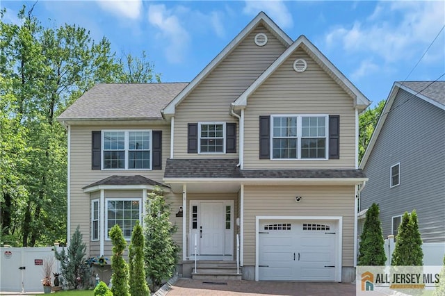 traditional-style home with an attached garage, fence, and decorative driveway