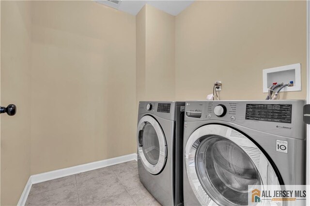 laundry area featuring independent washer and dryer, baseboards, and tile patterned floors