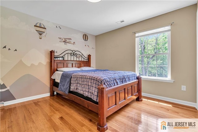 bedroom with baseboards, multiple windows, and light wood-style floors