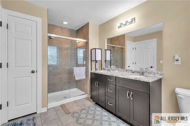 full bathroom featuring a shower stall, tile patterned floors, double vanity, and toilet