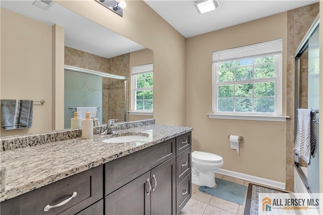 bathroom with a shower stall, tile patterned floors, vanity, toilet, and baseboards
