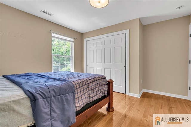 bedroom featuring baseboards, light wood-style floors, and a closet