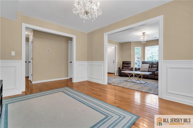 foyer entrance featuring a chandelier, hardwood / wood-style flooring, wainscoting, and a decorative wall