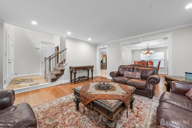 living room featuring light wood-type flooring, an inviting chandelier, and crown molding