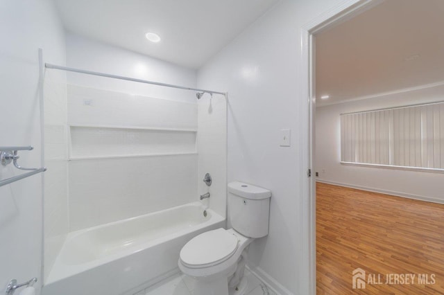 bathroom featuring toilet, baseboards, shower / bath combination, and wood finished floors