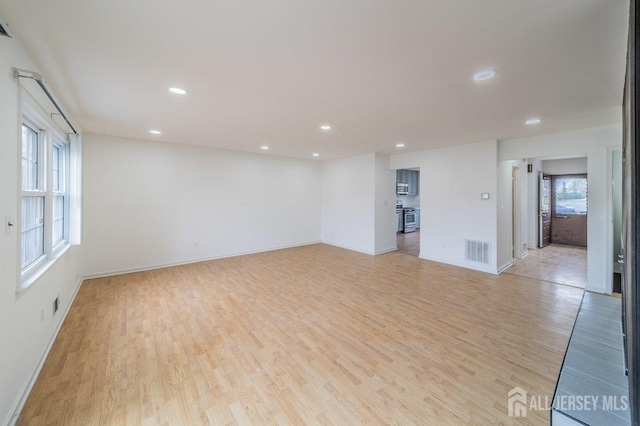empty room with light wood-style floors, recessed lighting, and baseboards