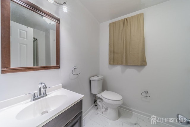 bathroom with baseboards, toilet, vanity, and marble finish flooring
