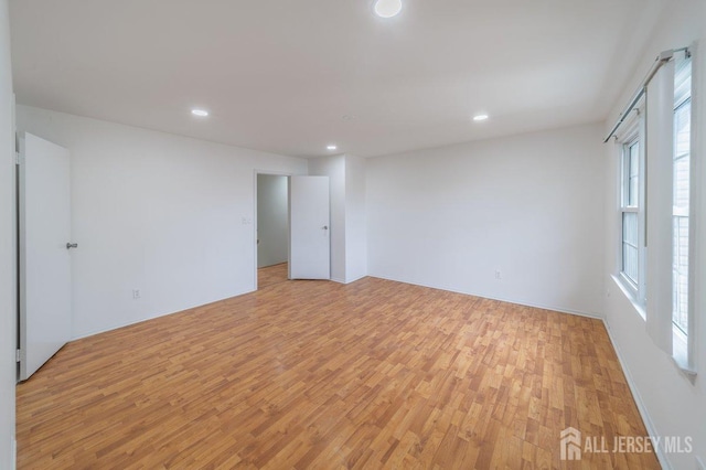 empty room with light wood-style flooring and recessed lighting