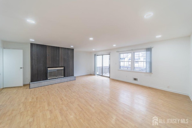 unfurnished living room featuring light wood-style flooring, recessed lighting, a tiled fireplace, and baseboards
