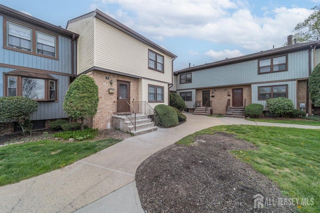 multi unit property featuring brick siding and a front lawn