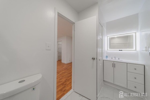 bathroom with toilet, vanity, and marble look tiles