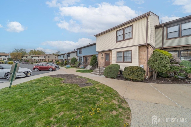 townhome / multi-family property with a residential view, a front lawn, and uncovered parking
