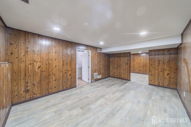 finished below grade area with wooden walls, washer / dryer, light wood-style floors, and recessed lighting