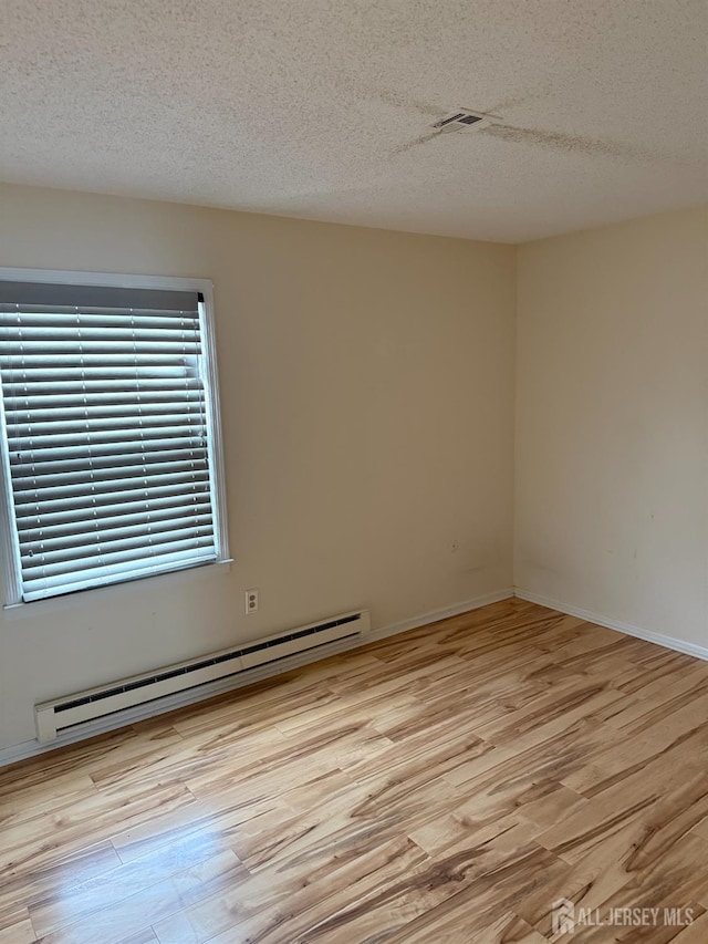 469-O New Haven Way, Monroe, NJ 08831 - empty room with a baseboard heating unit, a textured ceiling, wood finished floors, and baseboards
