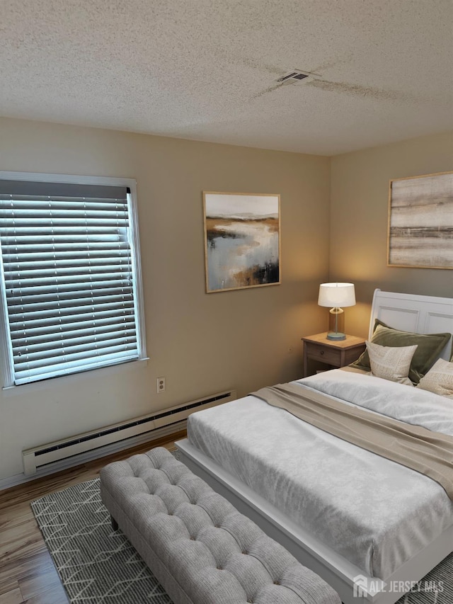 469-O New Haven Way, Monroe, NJ 08831 - bedroom with a baseboard heating unit, a textured ceiling, and wood finished floors